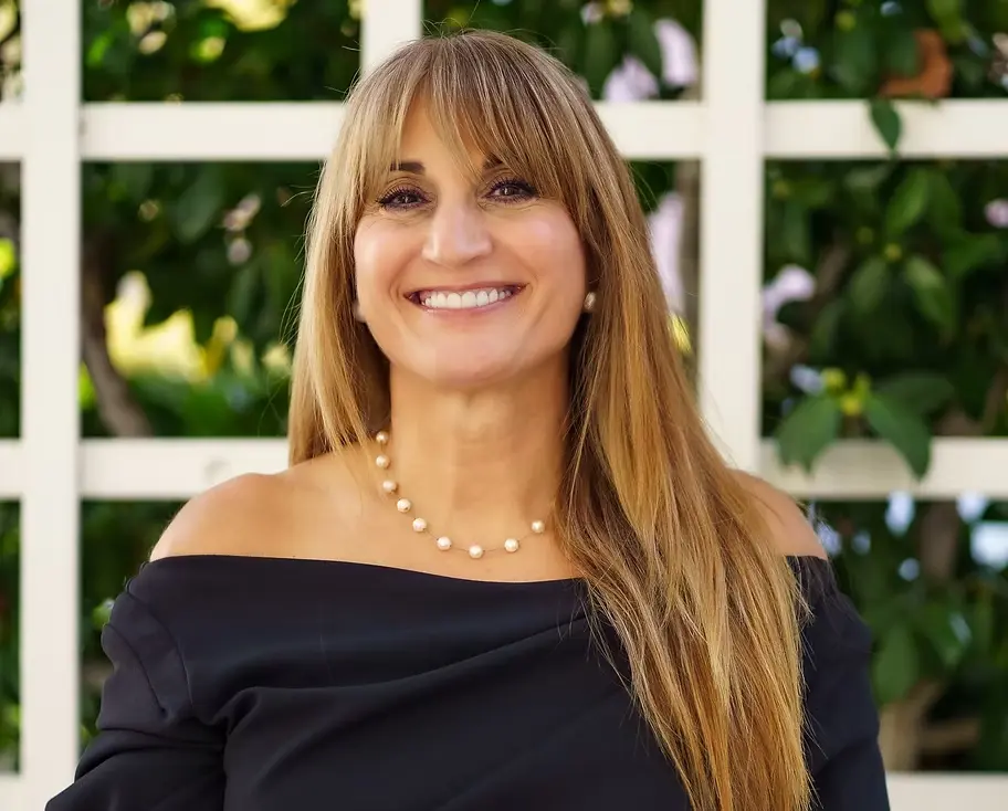 Smiling woman in black dress outdoors.